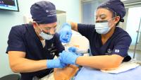Two nurse anesthesia students practicing clinical skills on a simulation manikin.